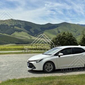 Roadside verge with parked car and hills beyond. Rural Southland, New Zealand.
