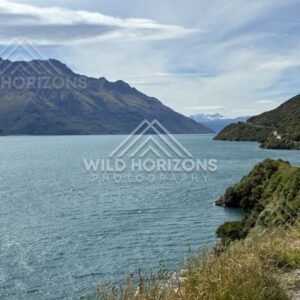 Curving shoreline with deep blue lake and mountains. Kingston, New Zealand.