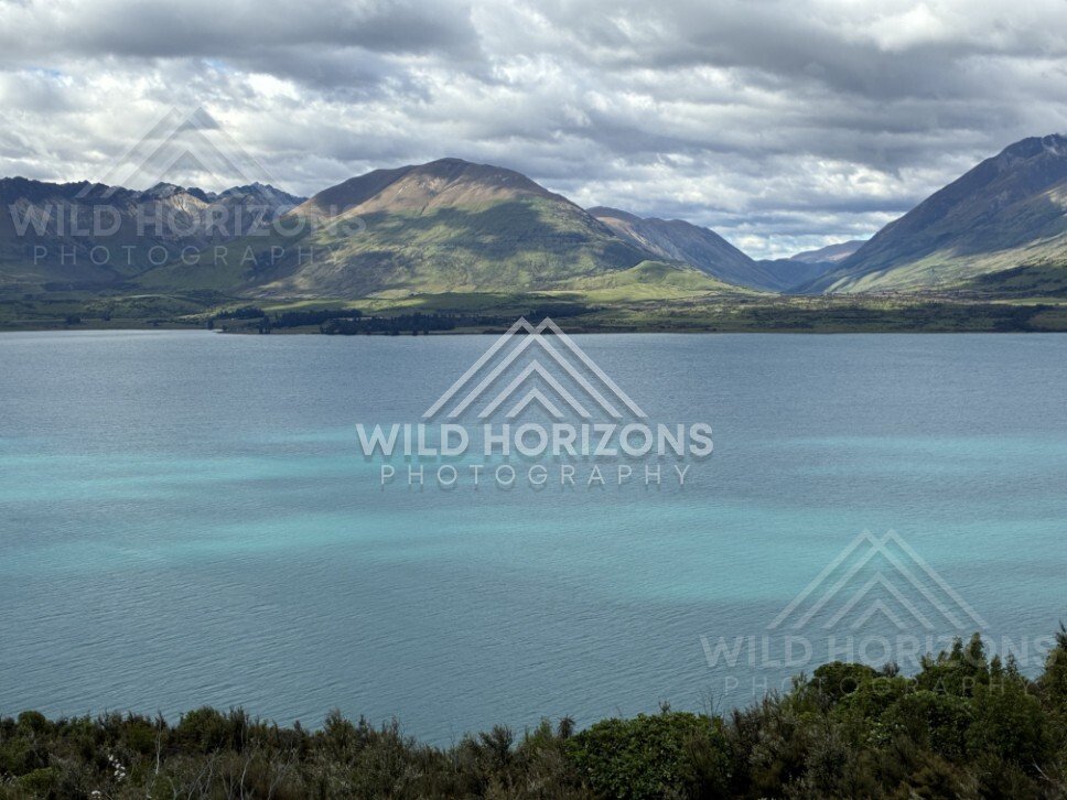 Still lake with mountain reflections under cloud. Glenorchy, New Zealand.