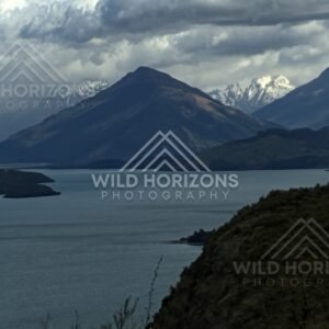 Moody lake beneath dark mountain and heavy cloud. Glenorchy, New Zealand.