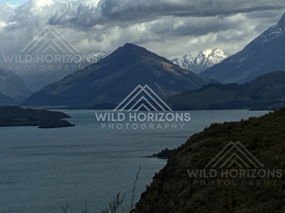 Moody lake beneath dark mountain and heavy cloud. Glenorchy, New Zealand.