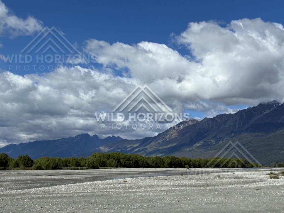 Wide riverbed with mountain range under scattered cloud. Glenorchy, New Zealand.