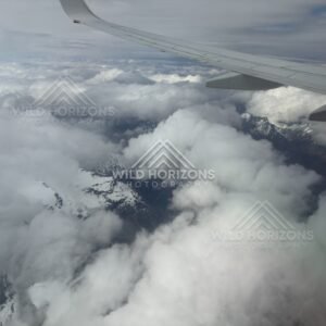 Aircraft wing above layered cloud and distant peaks. Queenstown, New Zealand.
