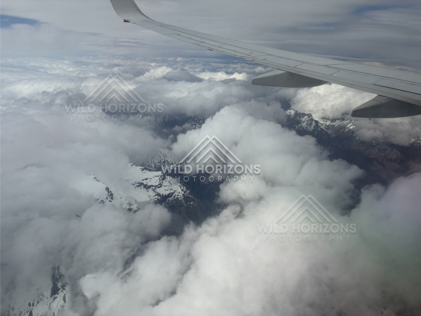 Aircraft wing above layered cloud and distant peaks. Queenstown, New Zealand.