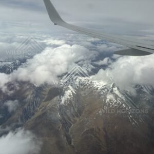 Aircraft wing above rugged alpine terrain and cloud. Queenstown, New Zealand.