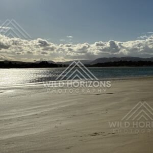Wide sandy beach with reflective wet sand. Surat Bay, New Zealand.