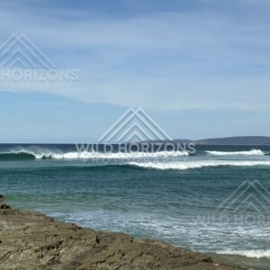 Rocky shoreline with waves rolling in. Helena Falls Beach, New Zealand.