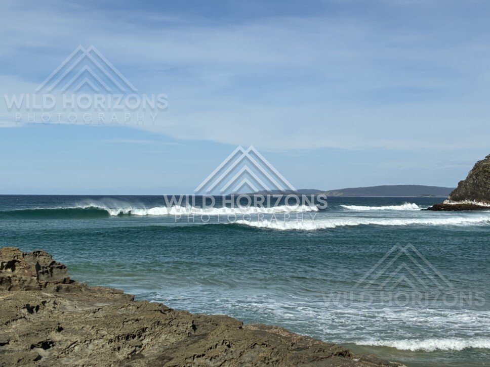 Rocky shoreline with waves rolling in. Helena Falls Beach, New Zealand.