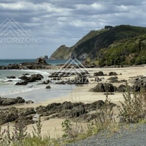 Rocky beach and cliffs beneath cloudy sky. Nugget Point, New Zealand.