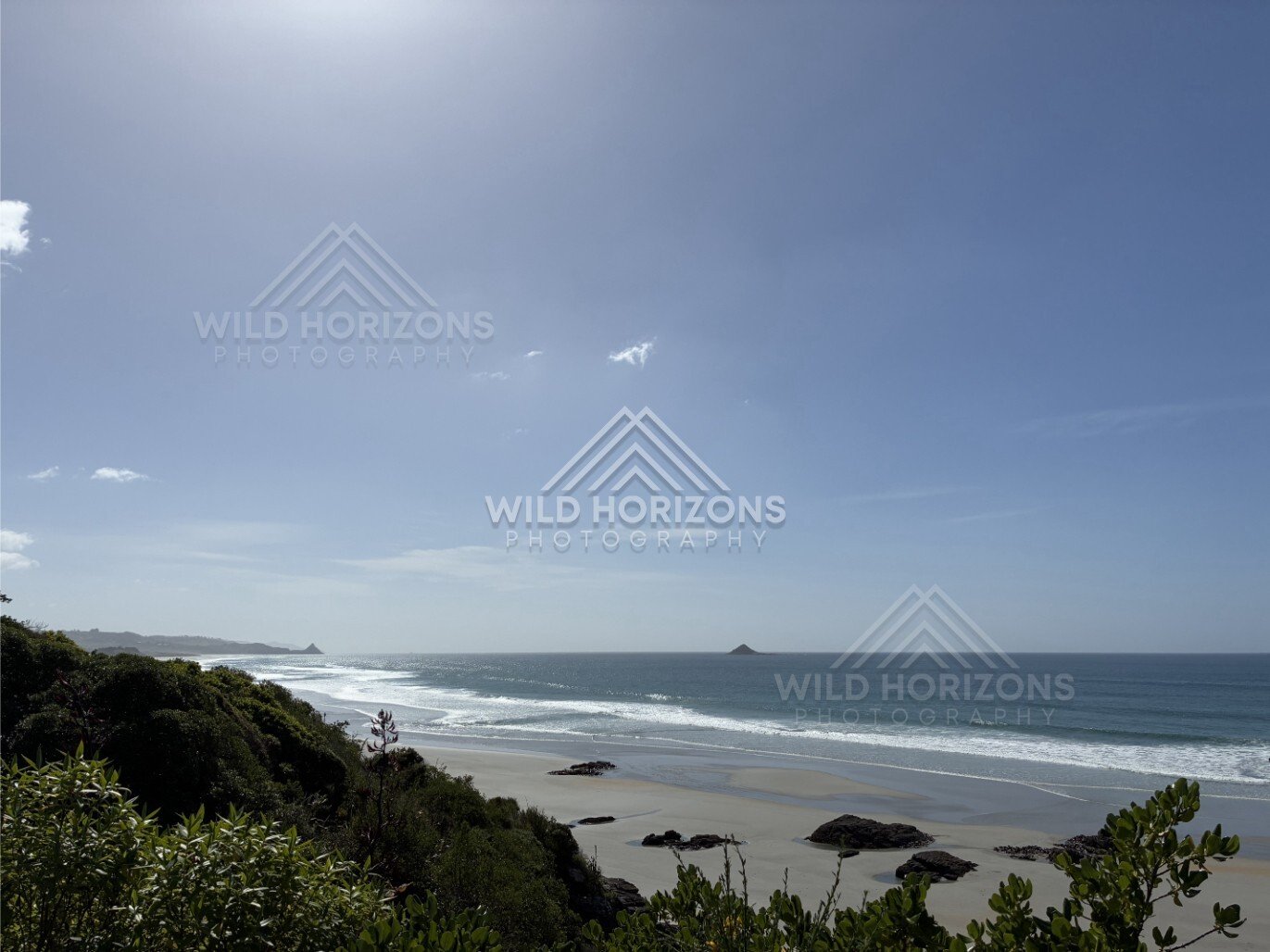 Rocky shoreline and headland beneath overcast sky. Blackhead Beach, New Zealand.