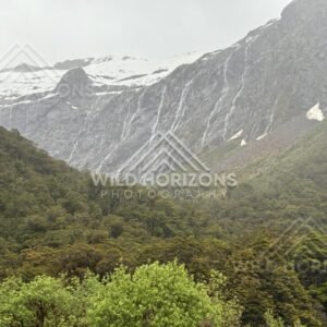 Waterfall Ribbons Across a Snow-Edged Fiordland Valley Wall. Milford Road, New Zealand.