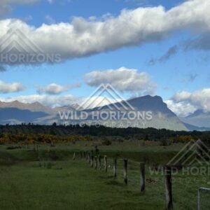 Fence Line Across Pasture with Mountains and Cloud. Milford Road, New Zealand.
