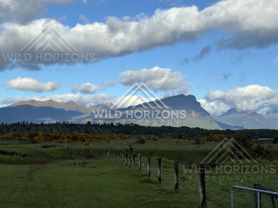 Fence Line Across Pasture with Mountains and Cloud. Milford Road, New Zealand.