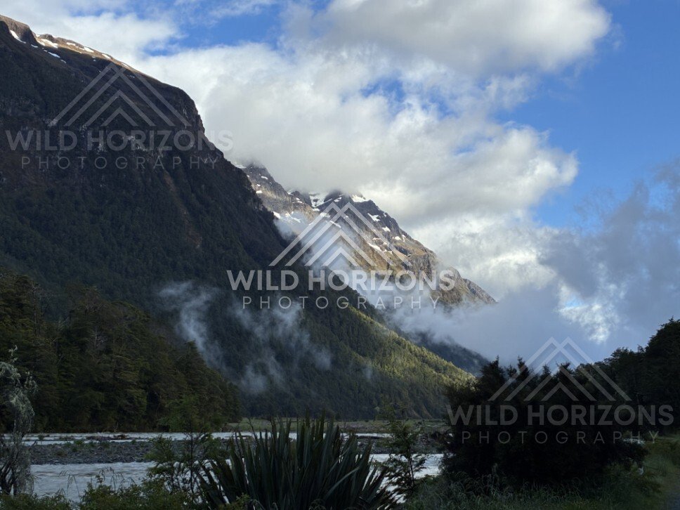 Mountain Slopes and River Flats Under Clearing Cloud. Milford Road, New Zealand.