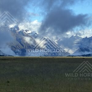 Mountain Valley with Sunlit Peaks and Lifting Cloud. Milford Road, New Zealand.