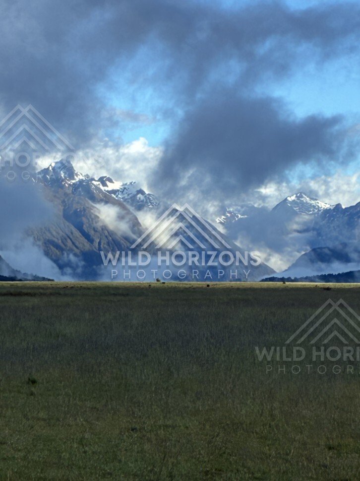 Mountain Valley with Sunlit Peaks and Lifting Cloud. Milford Road, New Zealand.