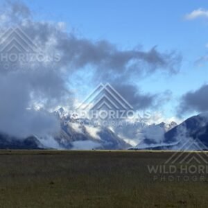 Snowy Fiordland Peaks Under Dark Cloud Above Plains. Milford Road, New Zealand.