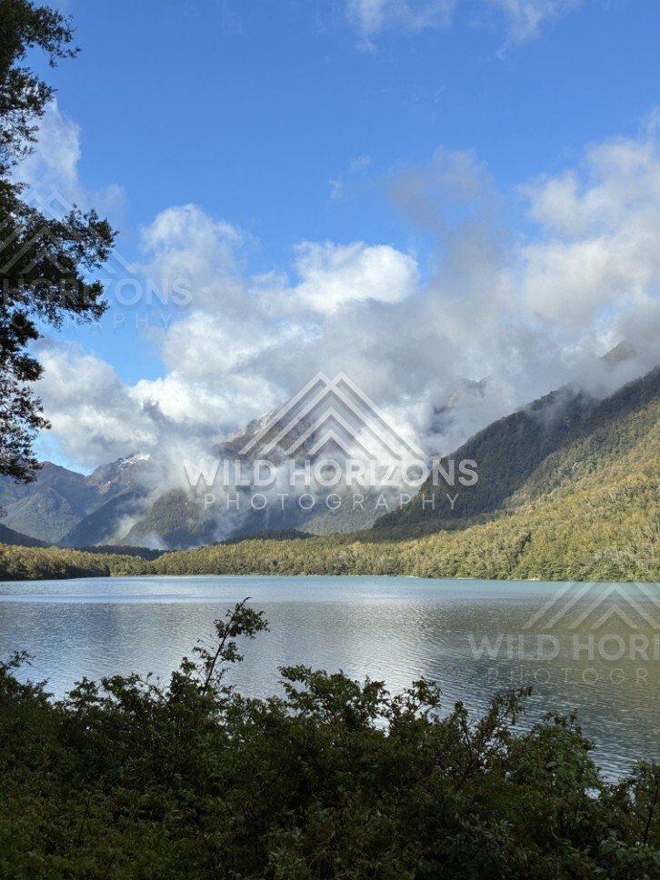 Mountain Lake with Cloud-Wrapped Peaks Beyond. Milford Road, New Zealand.