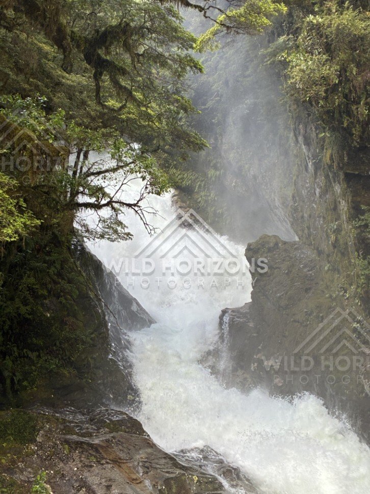 Powerful Waterfall Crashing Through a Narrow Gorge. Milford Road, New Zealand.