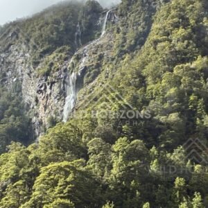 Large Waterfall on a Steep Forested Mountainside. Milford Road, New Zealand.