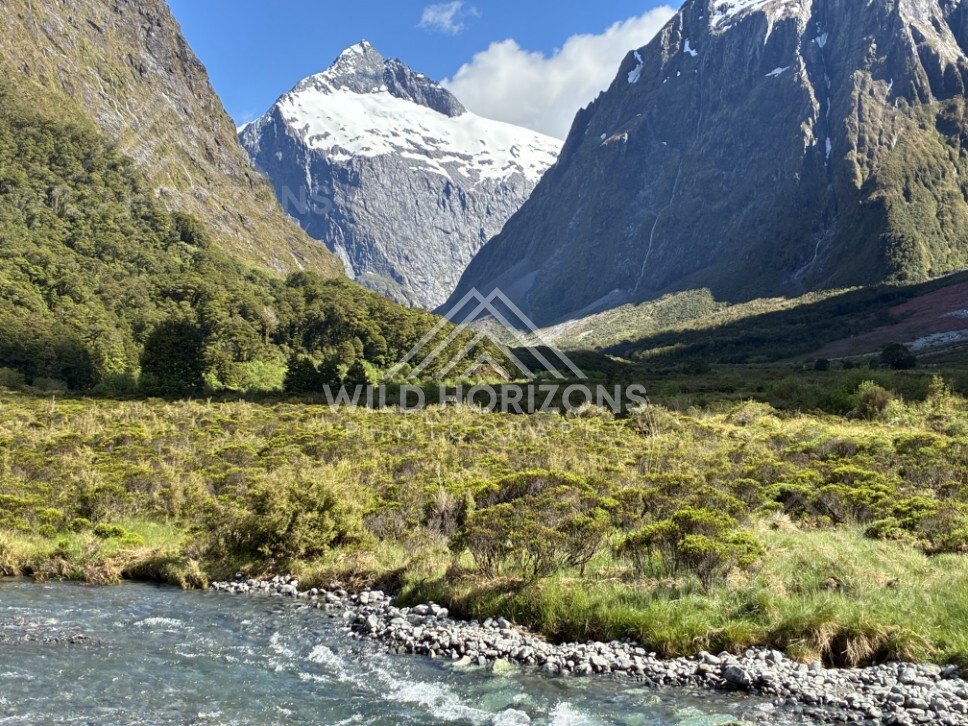 River Foreground with Snow-Capped Mountains and Waterfall Thread. Milford Road, New Zealand.