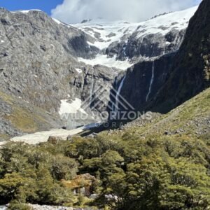 Twin Tall Waterfalls Dropping from a Snow-Dusted Cliff. Milford Road, New Zealand.