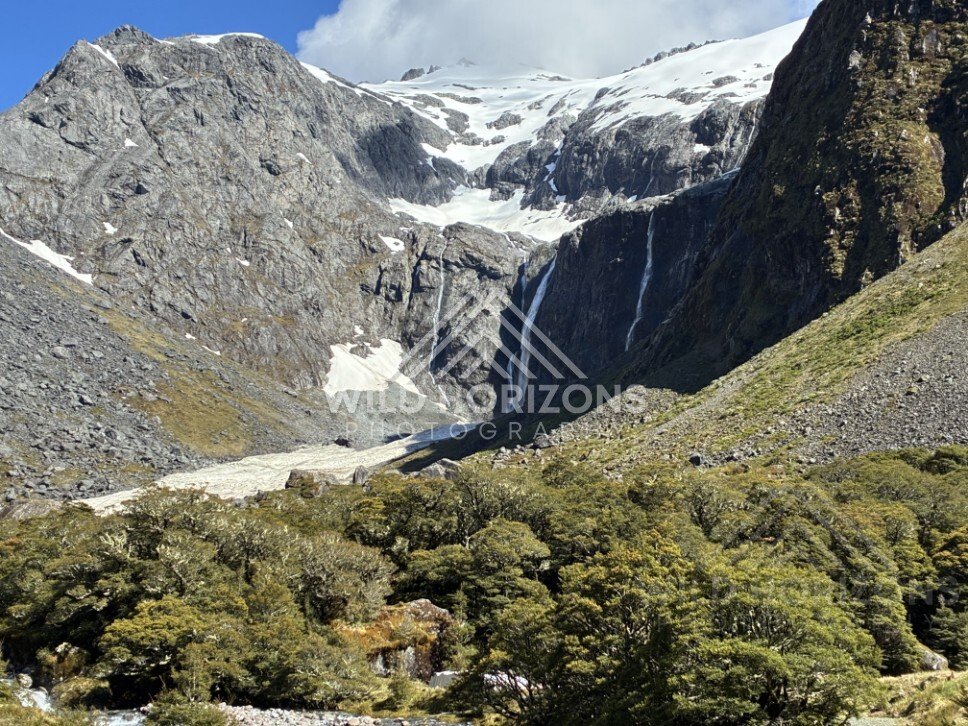 Twin Tall Waterfalls Dropping from a Snow-Dusted Cliff. Milford Road, New Zealand.