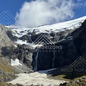 Tall Waterfall Pouring from a Snow-Capped Plateau into an Alpine Basin. Milford Road, New Zealand.