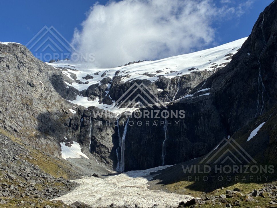 Tall Waterfall Pouring from a Snow-Capped Plateau into an Alpine Basin. Milford Road, New Zealand.