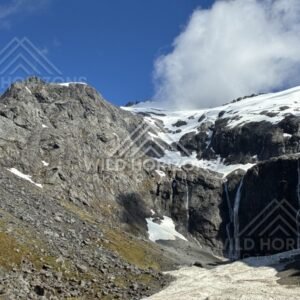 Rocky Basin with Snowfields and a Central Waterfall. Milford Road, New Zealand.