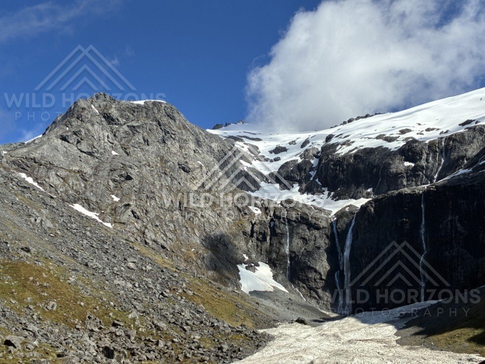 Rocky Basin with Snowfields and a Central Waterfall. Milford Road, New Zealand.