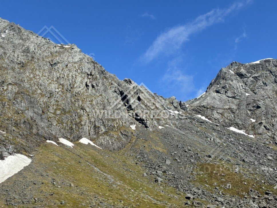 Rocky Ridgeline and Scree Slope with Patches of Snow. Milford Road, New Zealand.