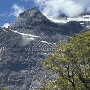 Jagged Mountain Peak with Snow Patches and Cloud Drift. Milford Road, New Zealand.