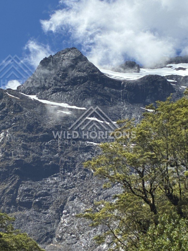 Jagged Mountain Peak with Snow Patches and Cloud Drift. Milford Road, New Zealand.
