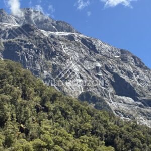 Steep Granite Face with Tall Waterfall and Forest Below. Milford Road, New Zealand.