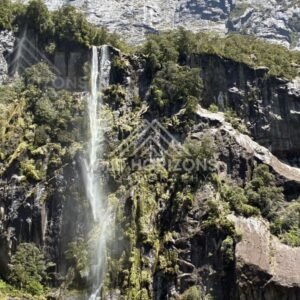 Narrow Waterfall Streaming Down a Sunlit Cliff Face. Milford Sound, New Zealand.