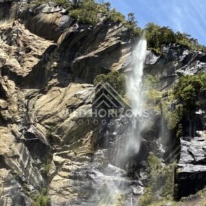 Waterfall and Mist Across a Sunlit Granite Wall. Milford Sound, New Zealand.