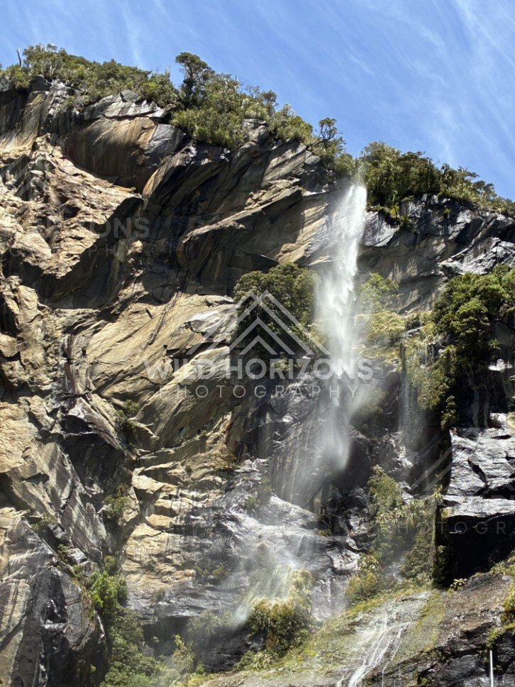Waterfall and Mist Across a Sunlit Granite Wall. Milford Sound, New Zealand.