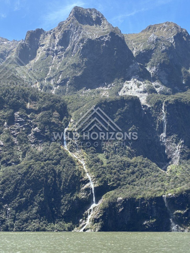 Tall Waterfall Dropping Over a Dark Fiord Cliff Face. Milford Sound, New Zealand.