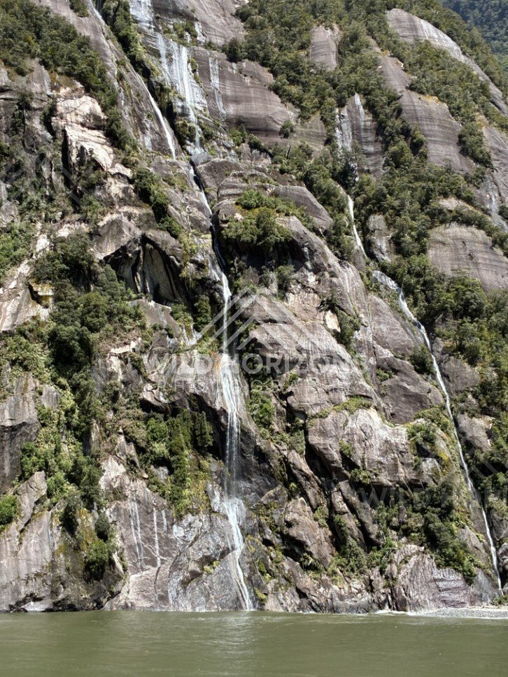Waterfall Rushing Down a Granite Rock Face Above the Fiord. Milford Sound, New Zealand.