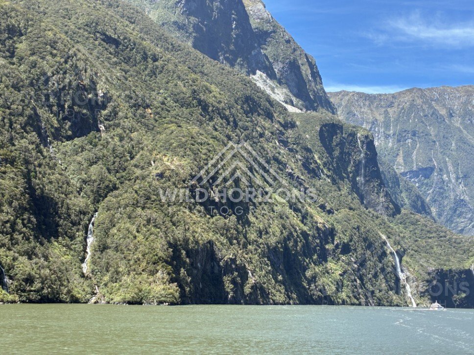 Fiord Wall and Waterway with Distant Waterfall Streaks. Milford Sound, New Zealand.
