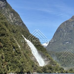 Tall Waterfall Dropping Through Dense Green Forest on Steep Slope. Milford Sound, New Zealand.
