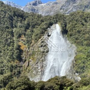 Tall Waterfall Framed by Dense Forest on a Sheer Mountainside. Milford Sound, New Zealand.