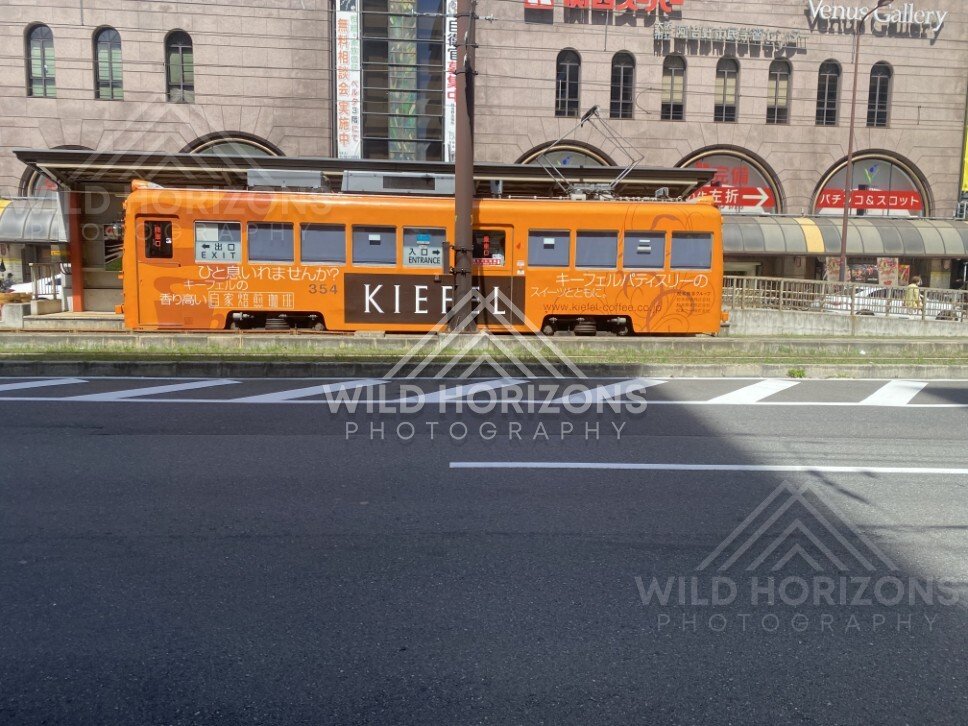 Orange Streetcar Passing Through a Sunlit Osaka Street. Osaka, Japan.