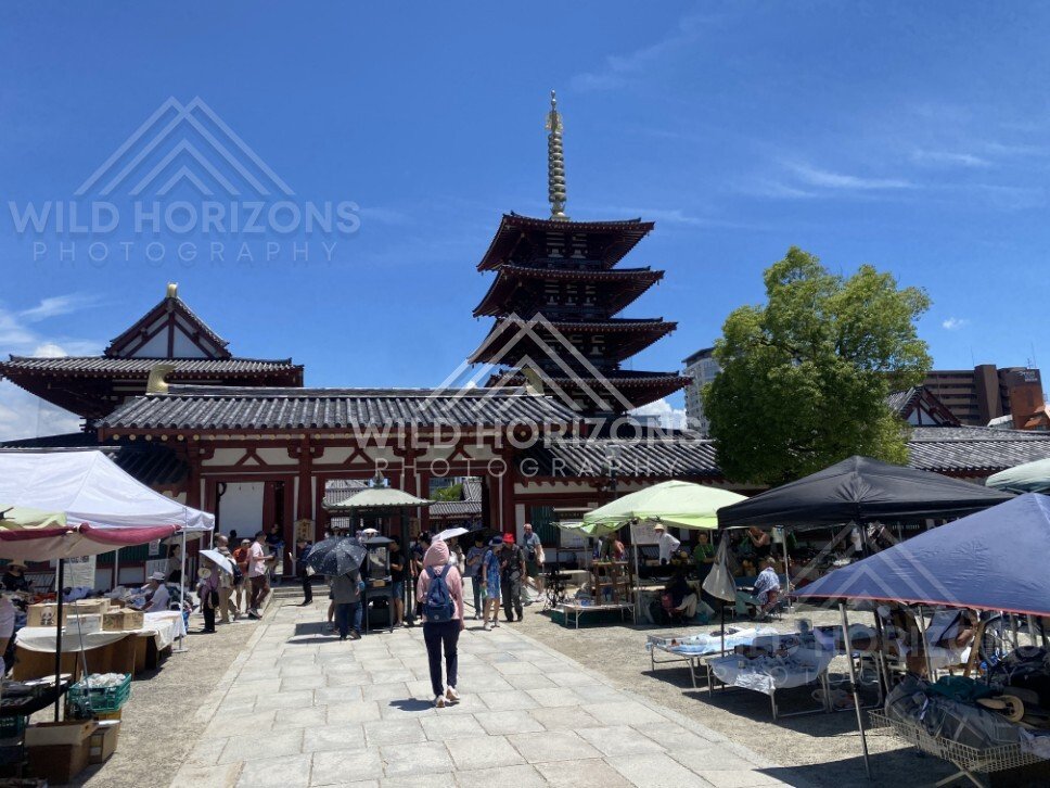 Temple Courtyard Market with Pagoda and Traditional Gate Under Summer Skies. Shitennoji Temple, Osaka, Japan.
