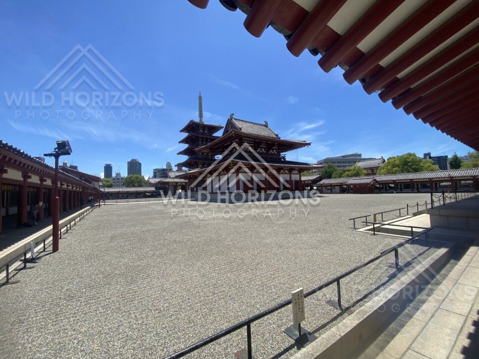 Wide Temple Courtyard Framed by Eaves with Pagoda and Hall in the Distance. Shitennoji Temple, Osaka, Japan.