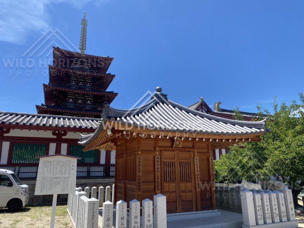 Small Shrine Pavilion with Tiled Roof and Pagoda Rising Behind the Walls. Shitennoji Temple, Osaka, Japan.