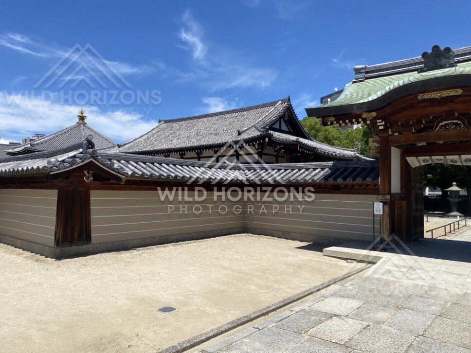 Temple Wall and Gate with Traditional Rooflines Beneath High Summer Clouds. Shitennoji Temple, Osaka, Japan.