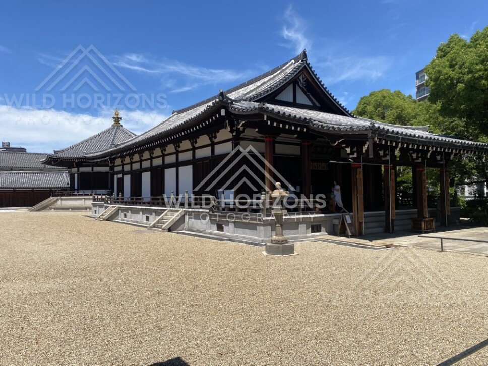 Traditional Temple Hall with Veranda and Stone Lantern Beside a Gravel Courtyard. Shitennoji Temple, Osaka, Japan.