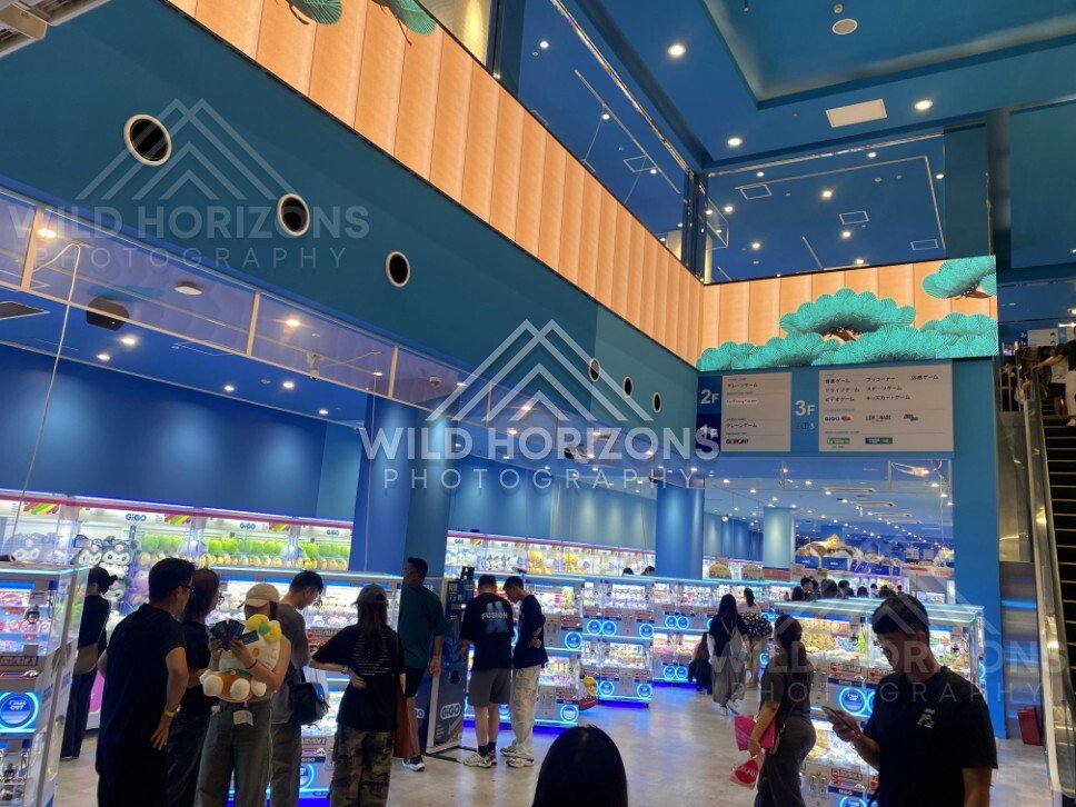Bright arcade interior with rows of capsule machines and visitors. Dotonbori, Osaka, Japan.
